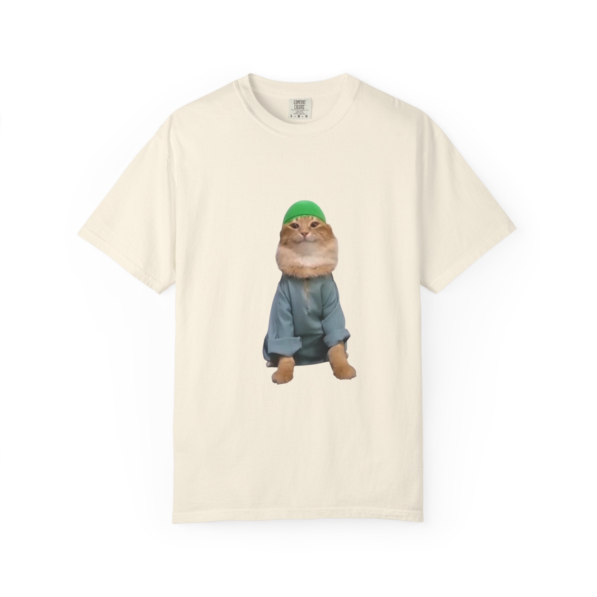 Beige t-shirt with a graphic of a cat wearing a green hat and blue jacket on a white background