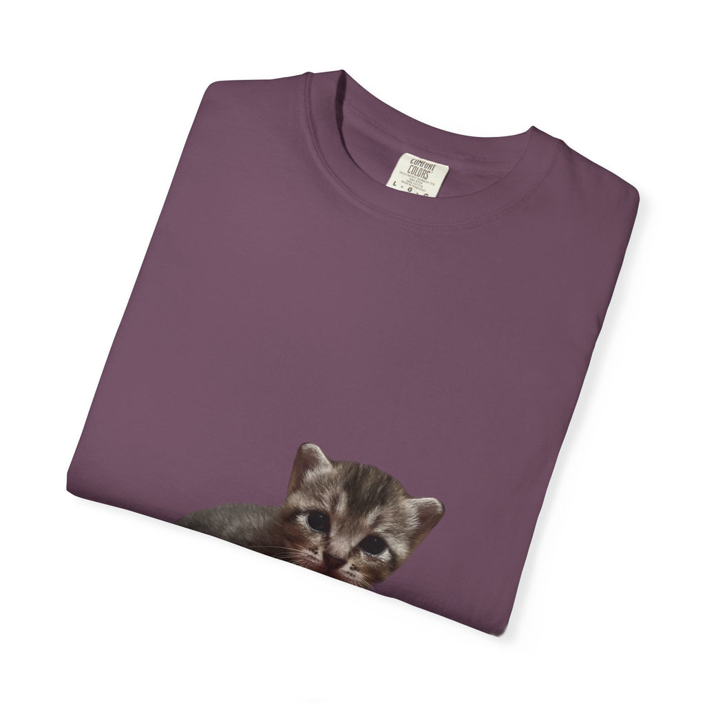 Folded purple t-shirt with a kitten graphic on a white background