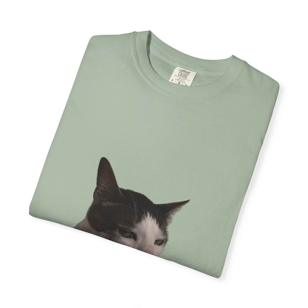 Folded green t-shirt with a cat's face printed on it against a white background