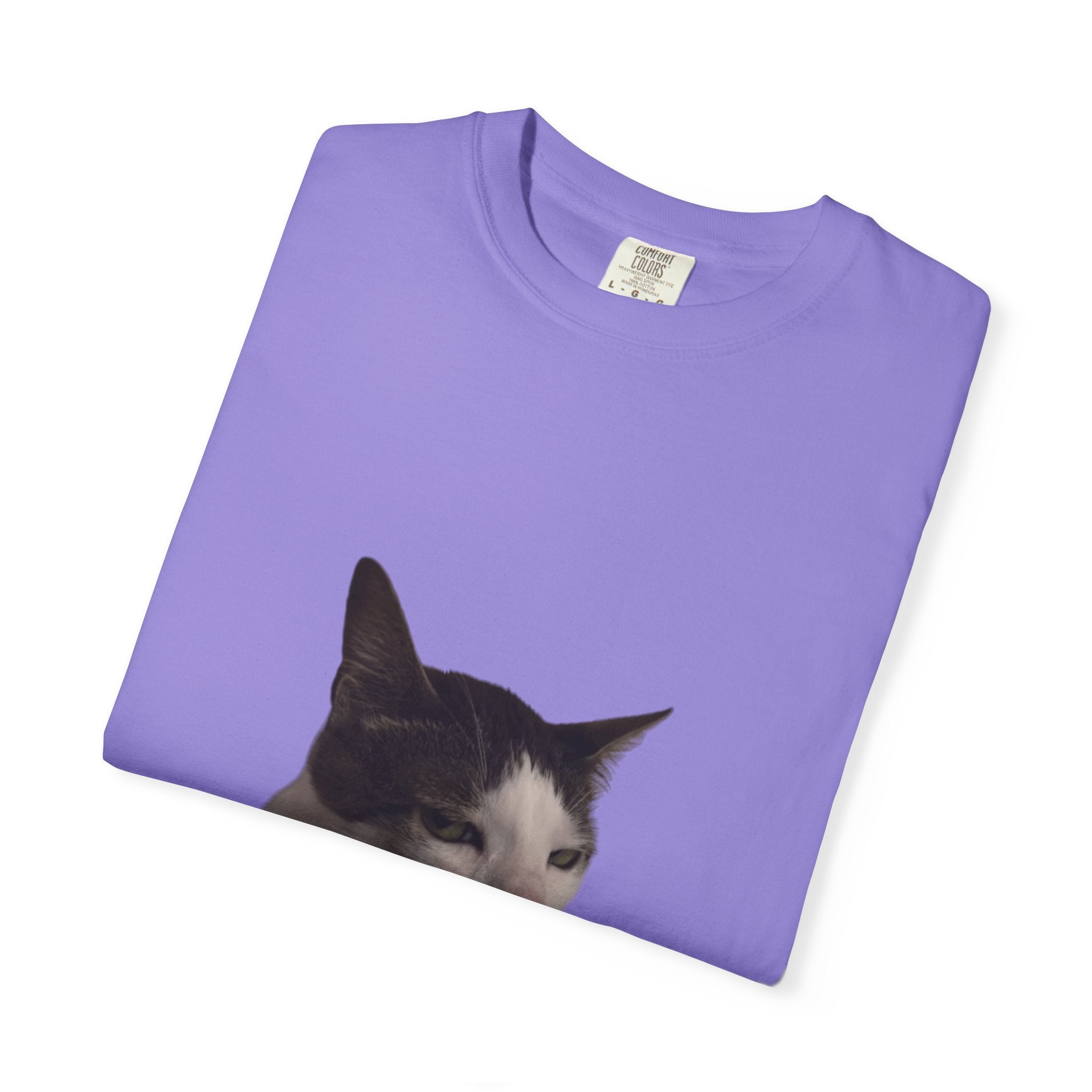 Folded purple t-shirt with a cat's head peeking out on a white background