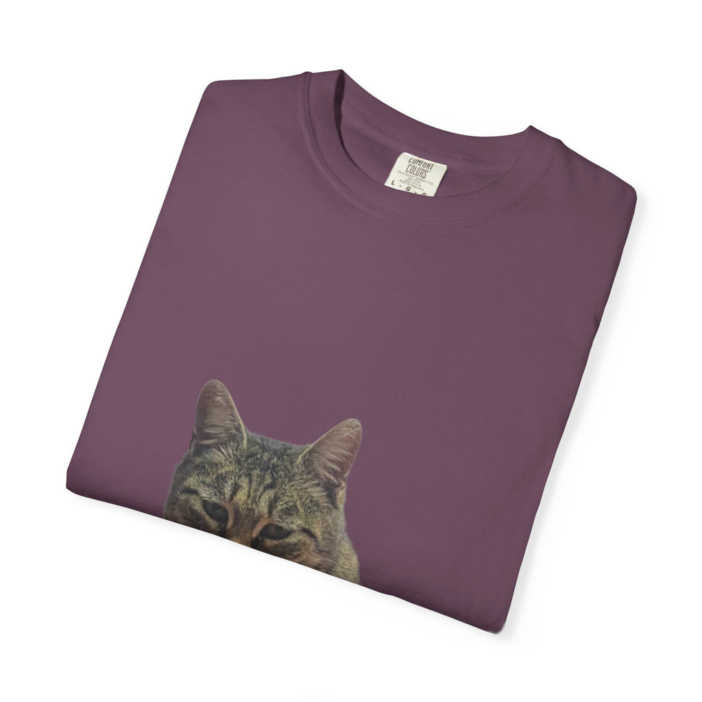 Folded purple t-shirt with a cat's face print on a white background
