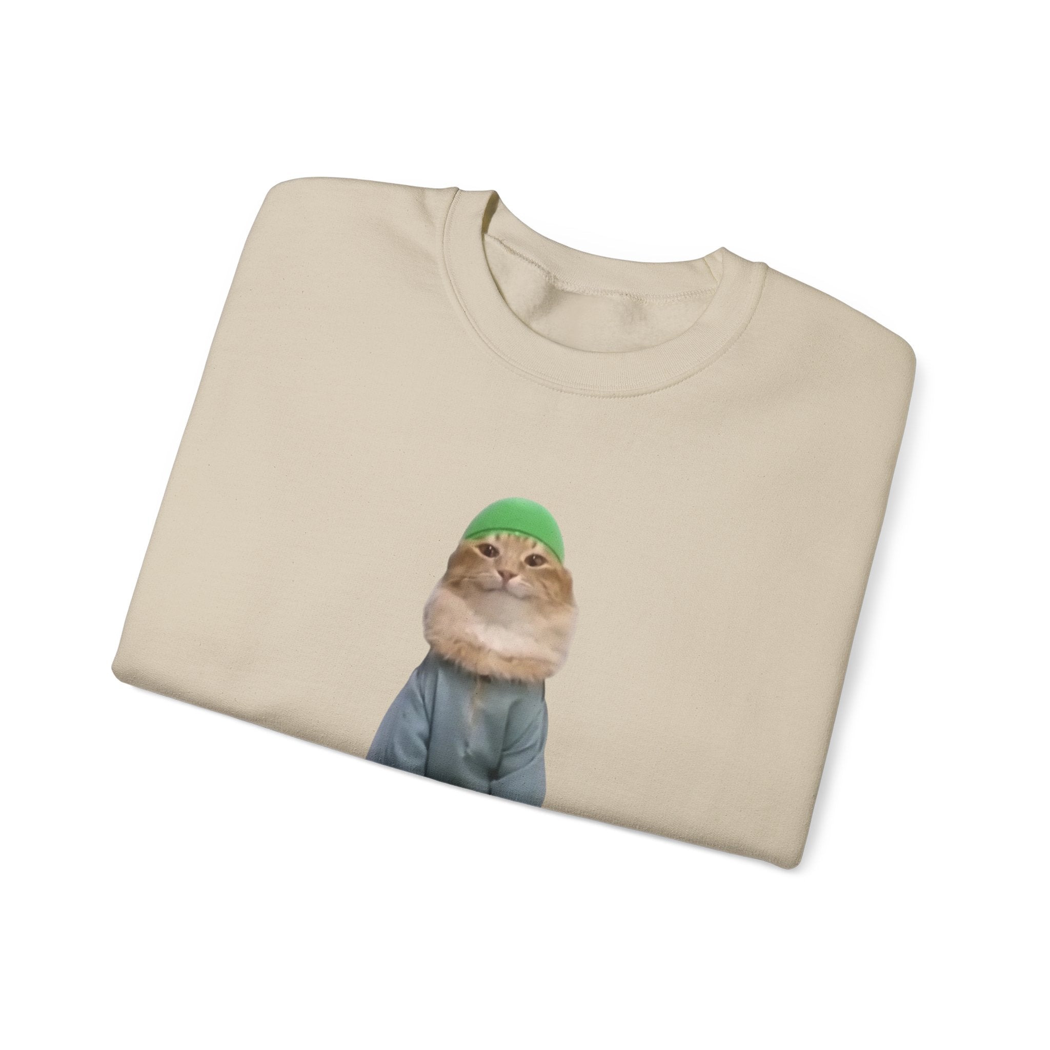Beige t-shirt with a graphic of a cat wearing a green beanie on a white background
