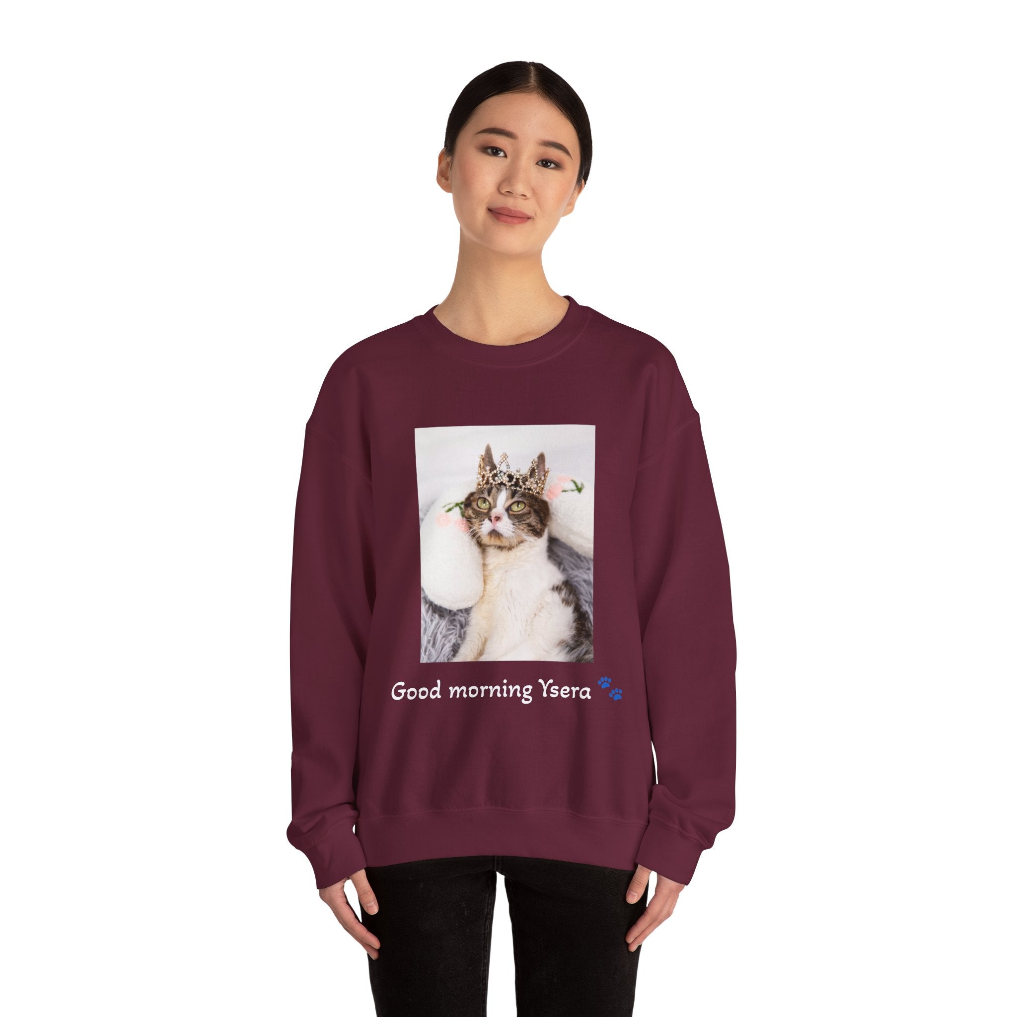 Person wearing a maroon sweatshirt with a cat graphic and text on a white background