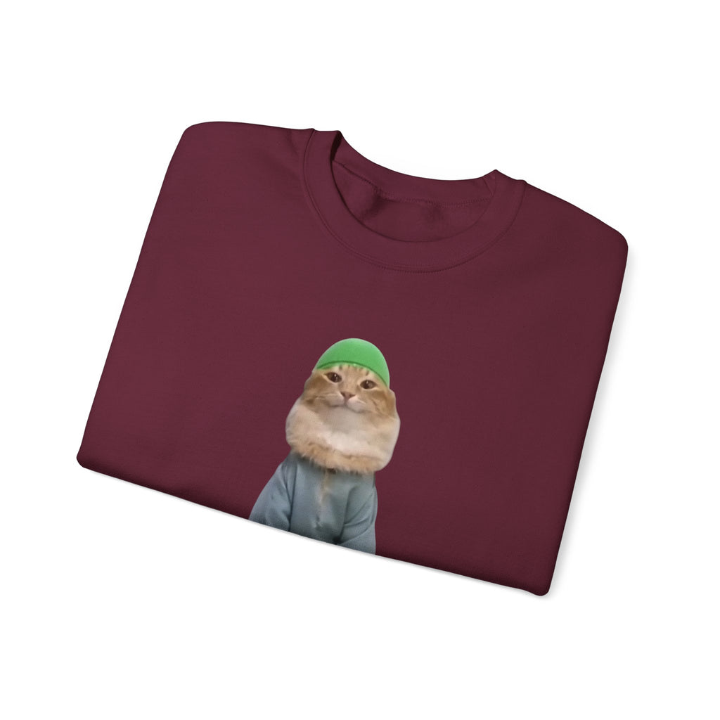 Folded maroon sweatshirt with a cat wearing a green beanie design on a white background
